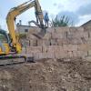 Treballant amb peçes de pedra d'escullera de grans dimensions per a la construcció del mur de contenció a Els Omellons. Les Garrigues